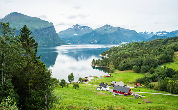 Small farm with red barn in the Norwegian countryside Small farm with red barn and white house in the Norwegian countryside with beautiful fjord and majestic mountains in the background red barn house stock pictures, royalty-free photos & images