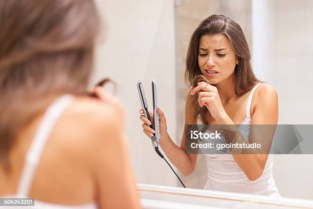 Woman Straightening Hair In Bathroom Stock Photo - Download Image Now - Women, Damaged, Problems