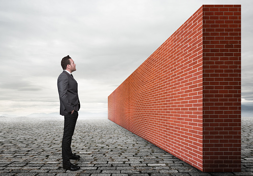 Businessman looking brick wall.