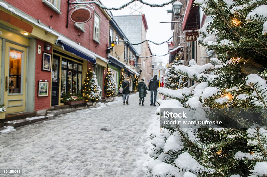 People on the Petit Champlain street in Quebec city People on the Petit Champlain street in Quebec city during a nice day of winter, Focus is on a Christmas tree (with snow and lights) on the right side, and people are all out of focus. Christmas Stock Photo