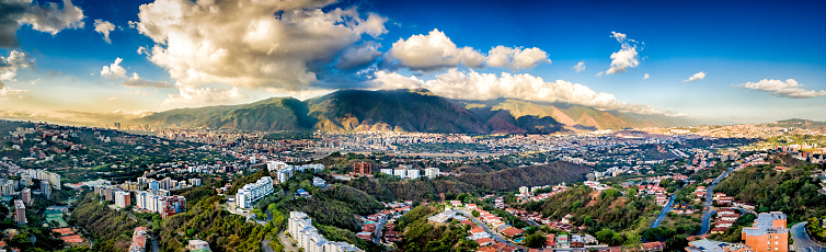 Panoramic image of eastern Caracas city aerial view at late afternoon. Venezuela.  Showing El Avila mountain also known as El Avila National Park (Guaraira Repano).  Santiago de Leon de Caracas, is the capital city of Venezuela and center of the Greater Caracas Area. It is located in the northern part of the country, following the contours of the narrow Caracas Valley and the \