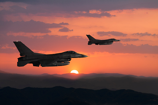 Two Fıghter Jet flying over the mountains at sunset