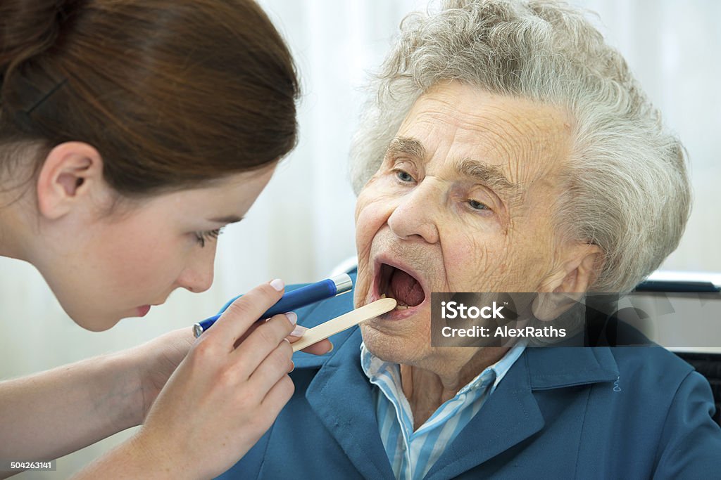 Medical exam Doctor examines elderly woman for sore throat Examining Stock Photo