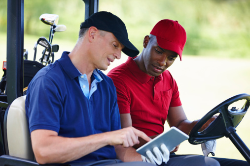 Shot of two men in a golf cart looking at a digital tablet