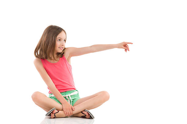 istock Girl sitting with legs crossed and pointing 504265283
