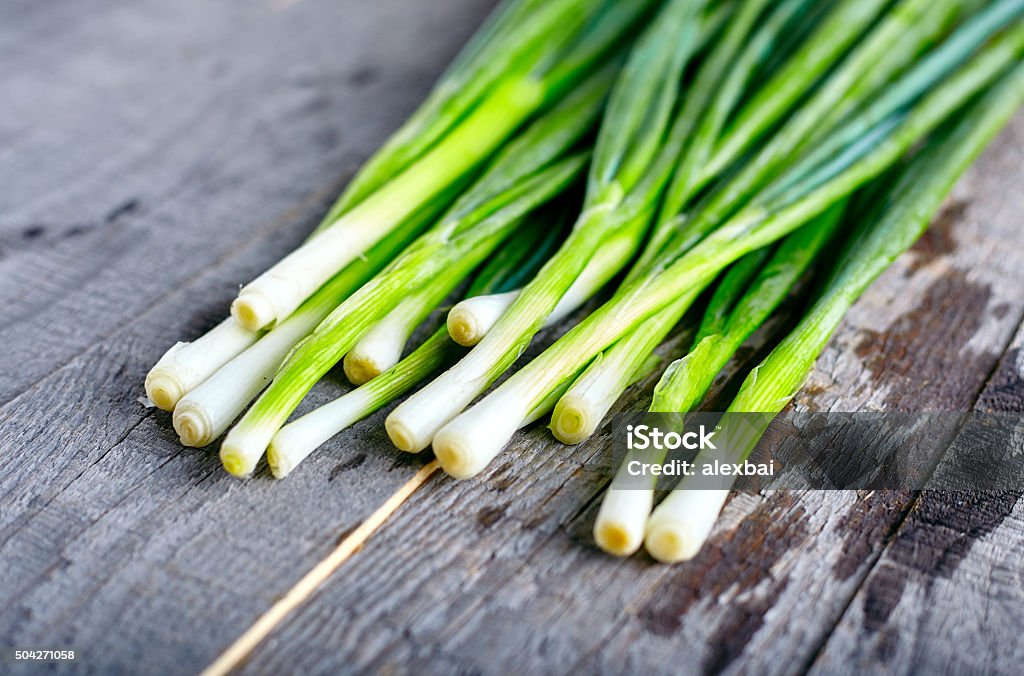 Bunch of fresh green onions Bunch of fresh green onions on dark or neutral wooden background Scallion Stock Photo