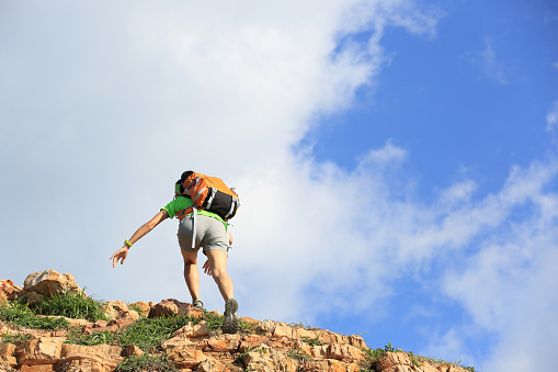 young woman backpacker climbing on  seaside mountain trail