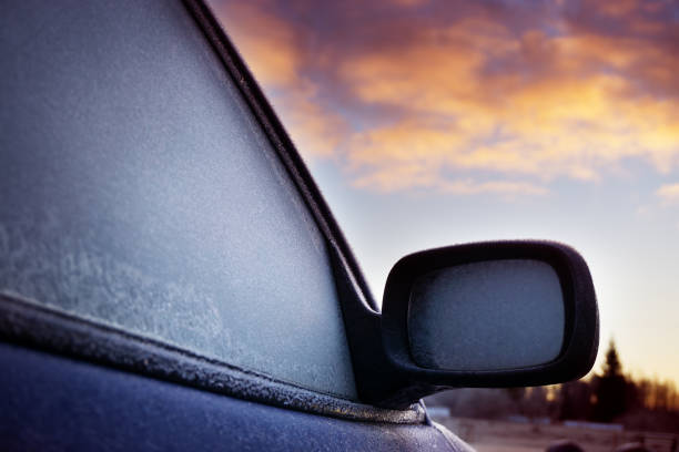 Car window and side mirror covered with ice in early morning