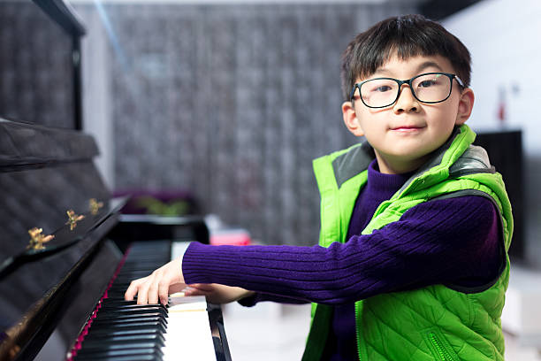 Asian cute boy playing piano at home