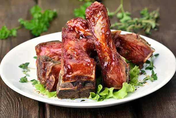 Roasted pork ribs on white plate over wooden table
