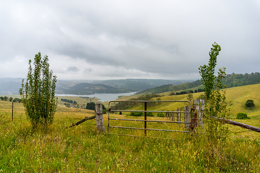 Farm fence with picturesque paddock hills and lake Lyell in the distance. Selective focus