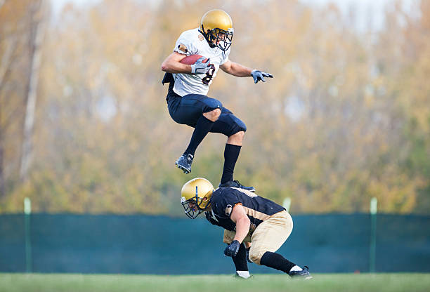 istock American football player jumping over his opponent during a match. 504281176