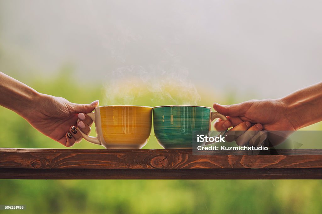 Hands holding mug with hot beverage, with tea Hands holding mug with hot beverage, with tea on a wooden stand outdoors in the countryside Tea - Hot Drink Stock Photo