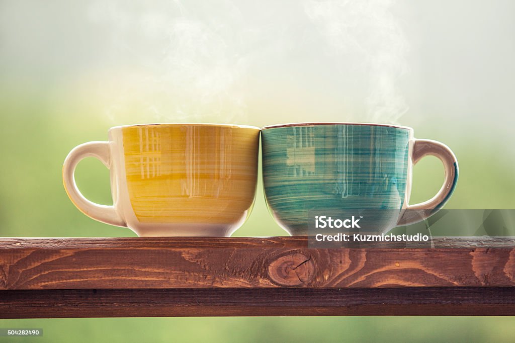 Mugs with a hot drink with tea on a wooden Mugs with a hot drink with tea on a wooden stand outdoors in the countryside Pair Stock Photo