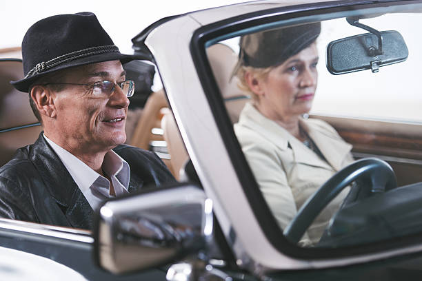 istock Mature old fashioned couple driving in convertible car. 504285256