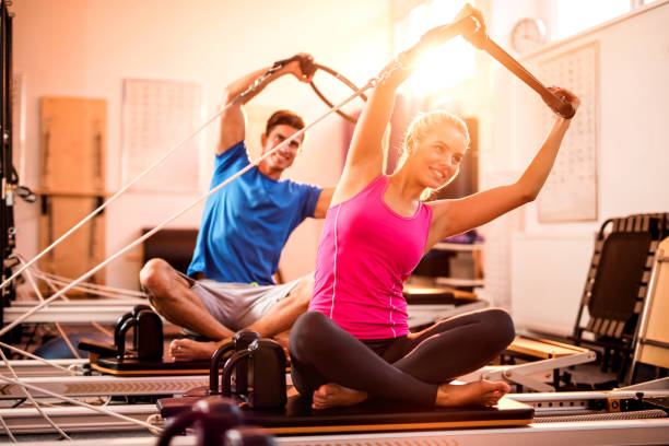 Young athletes doing stretching exercises on Pilates machines.
