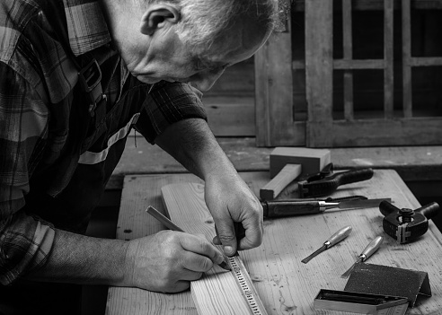 Senior carpenter marking a measurement on a wooden plank