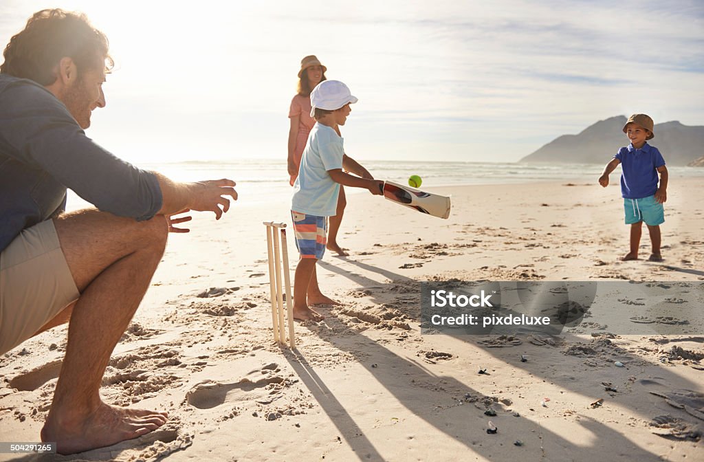 Future sports stars in training A happy young family playing cricket on the beach Sport of Cricket Stock Photo