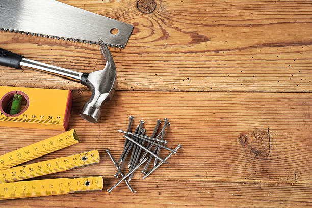 Handsaw, hammer, level, nails and folding ruler on wooden background stock photo