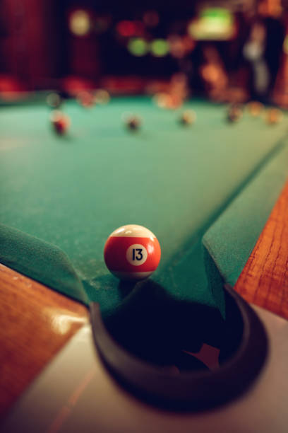 istock Pool ball number 13 about to enter the hole. 504299904