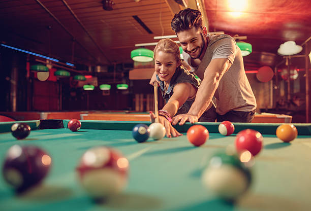 giovane coppia felice godendo di un gioco di biliardo. - pool game pool table aiming men foto e immagini stock
