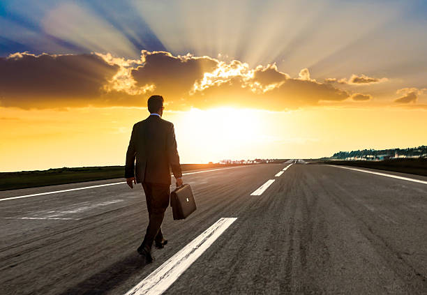 Entrepreneur walking for new opportunity Entrepreneur, carrying a briefcase, walking on an empty highway at sunset. road to success stock pictures, royalty-free photos & images