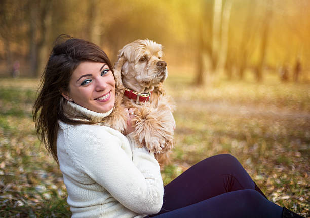 Happy punk woman playing with her dog, in the park on a sunny day. Hugging her.