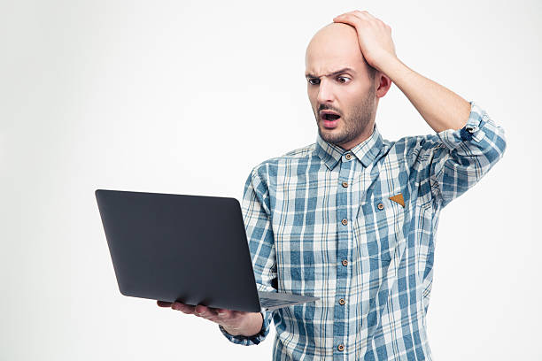 istock Amazed shocked man in plaid shirt holding and using laptop 504303788