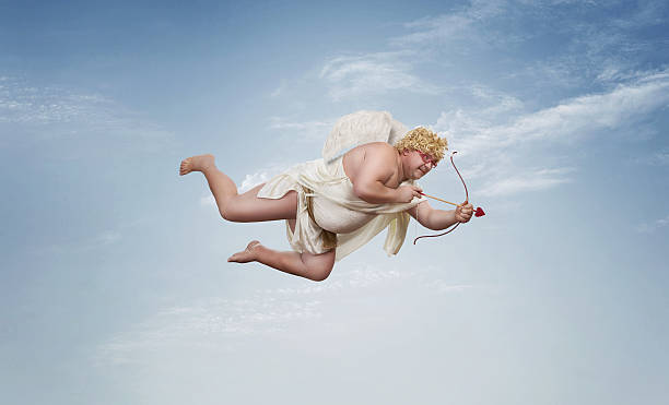 Funny overweight cupid Funny overweight cupid aiming with the arrow of love over clear blue sky with copy space cherub stock pictures, royalty-free photos & images