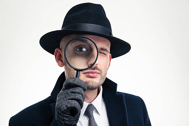 istock Funny concentrated inspector in black hat looking through the magnifier 504305846