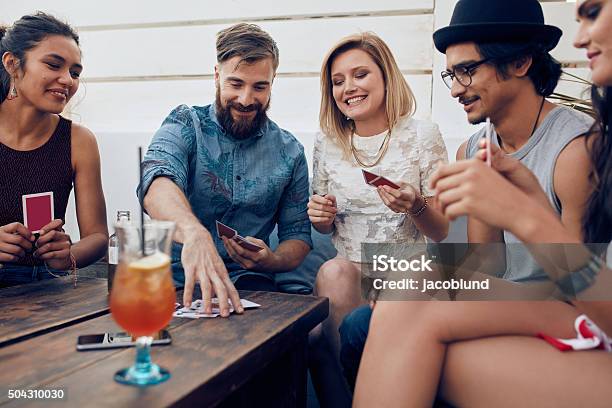 Group Of Friends In A Party Playing Cards Stock Photo - Download Image Now - Playing Card, Leisure Games, Friendship