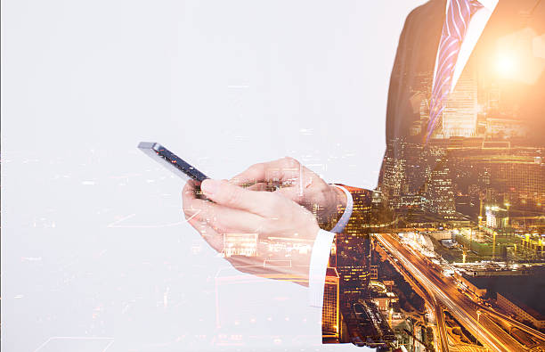 istock Businessman with phone double exposed with city 504310772