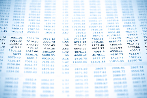 Blue tone macro picture of numbers on a data printout paper with selective focus.