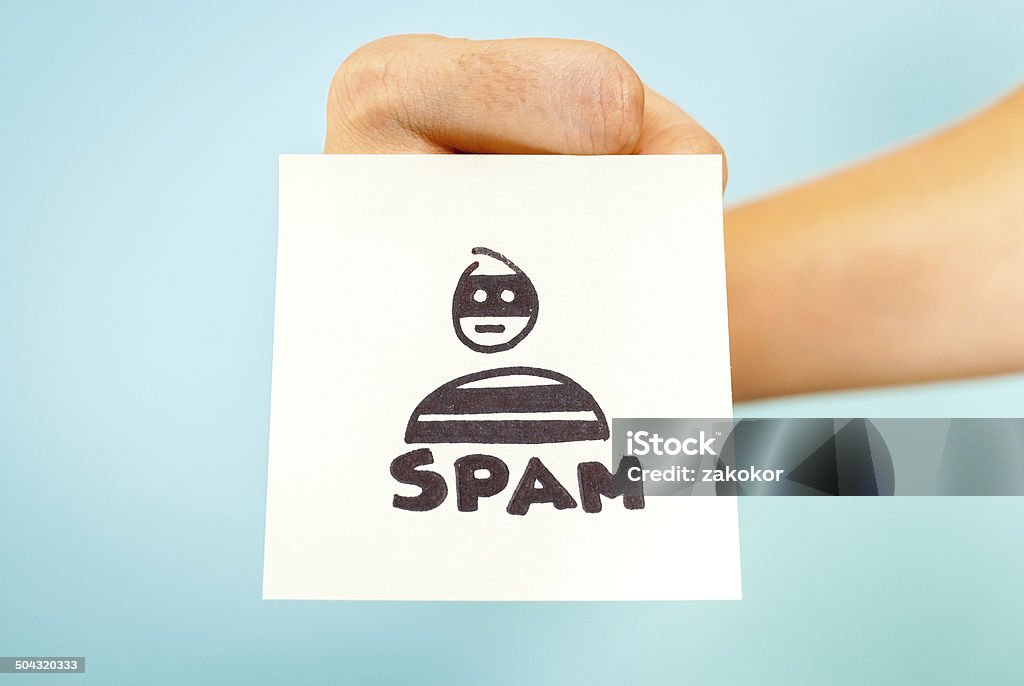 Fist with email spam word note blue background Hand with spam message on blue background. Social Media Stock Photo