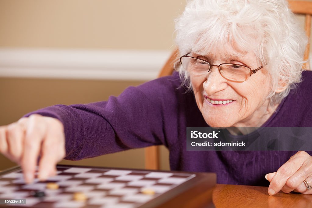 Senior Woman Playing Checkers A smiling 88 year old woman playing checkers. Checkers Stock Photo