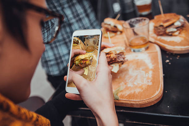 Taking Picture Of Burger Close Up Of Woman Taking Picture Of  Delicious Burger Using Smart Phone fast food restaurant photos stock pictures, royalty-free photos & images