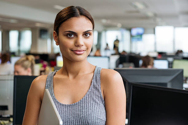 Businesswoman with tablet smiling towards camera in modern office Portrait of ethnic aboriginal Australian businesswoman in a office holding a laptop computer. Young female business professional at modern workplace in Australia. aborigine woman stock pictures, royalty-free photos & images