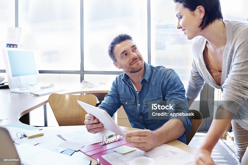 Making connections Shot of two coworkers using a tablet in a discussion Adult Stock Photo