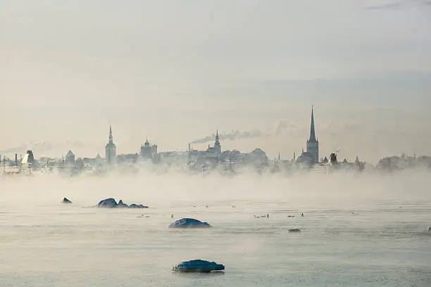 Cityscape of Tallinn over the waterfront in a cold day. -18 degrees Celsuis.  The sea is steaming cause of the cold outside.