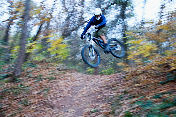 Mountain biker hits a jump during downhill race. Blurred motion.