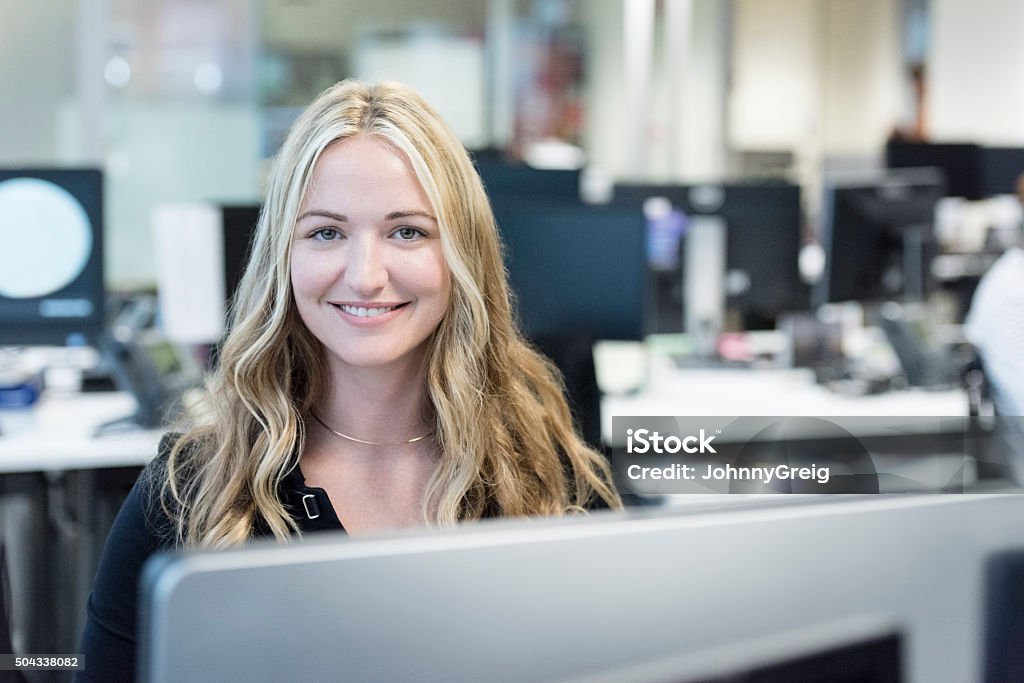 Businesswoman with long blond hair smiling towards camera Portrait of mid adult woman working in modern office on computer Office Stock Photo