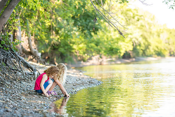 istock Two Young Girls Playing on Riverbank 504339544