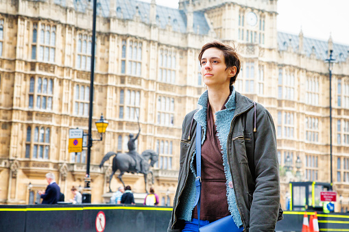 Young Androgynous British woman walking in Westminster London UK, looking ahead with a calm, confident expression.