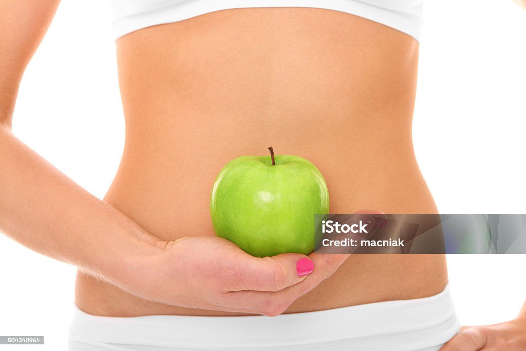 Be healthy! A picture of a woman holding a green apple in front of her fit belly Adult Stock Photo