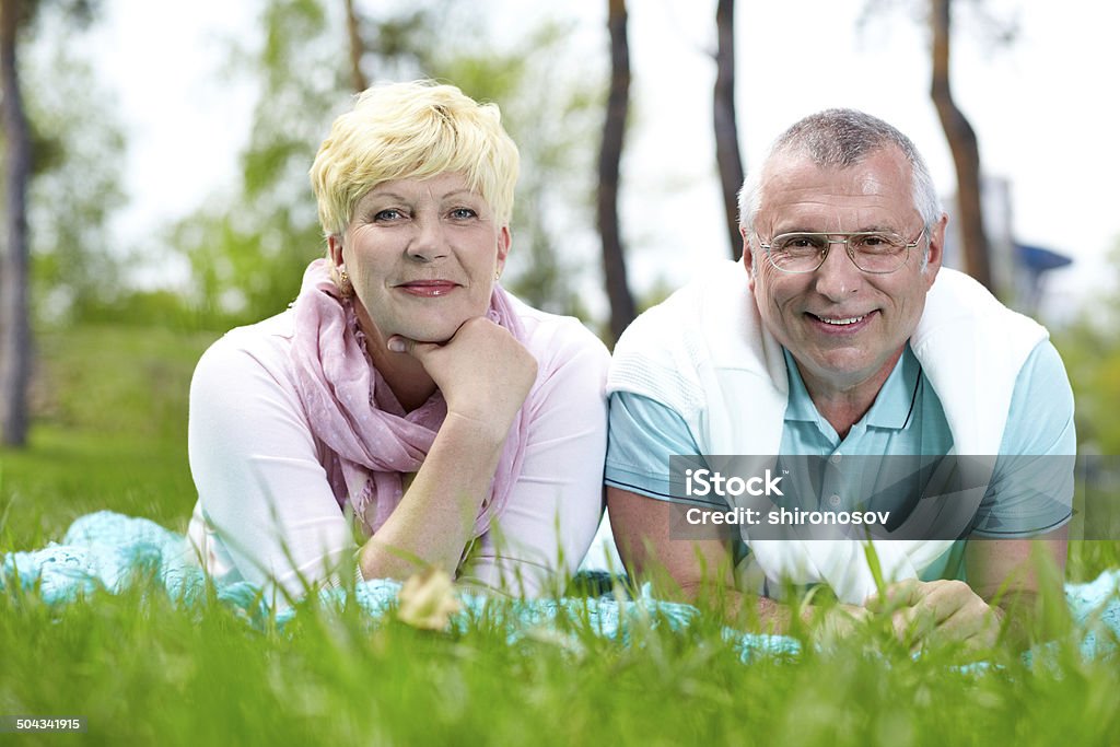 Lying on grass Happy mature couple lying on grass and having rest in summer Adult Stock Photo