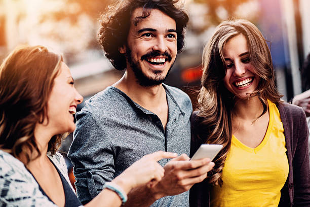 istock Smiling teenagers text messaging outdoors 504343640