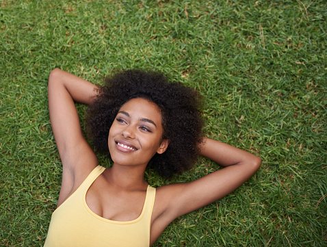 Portrait of a happy young woman lying on the grass