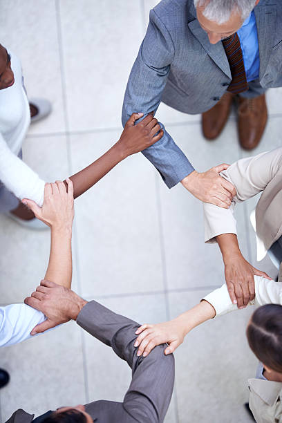 United in business Shot of a group of coworkers with their hands in a huddle arm in arm stock pictures, royalty-free photos & images