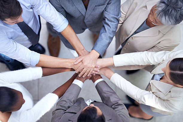 In diversity we will succeed Shot of a group of coworkers with their hands in a huddle hands clasped stock pictures, royalty-free photos & images