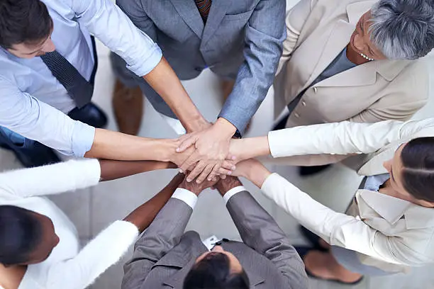 Shot of a group of coworkers with their hands in a huddle